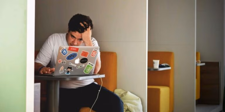 Young man peers into laptop screen looking looking distressed ‣ boss intelligence ‣ boss intelligence